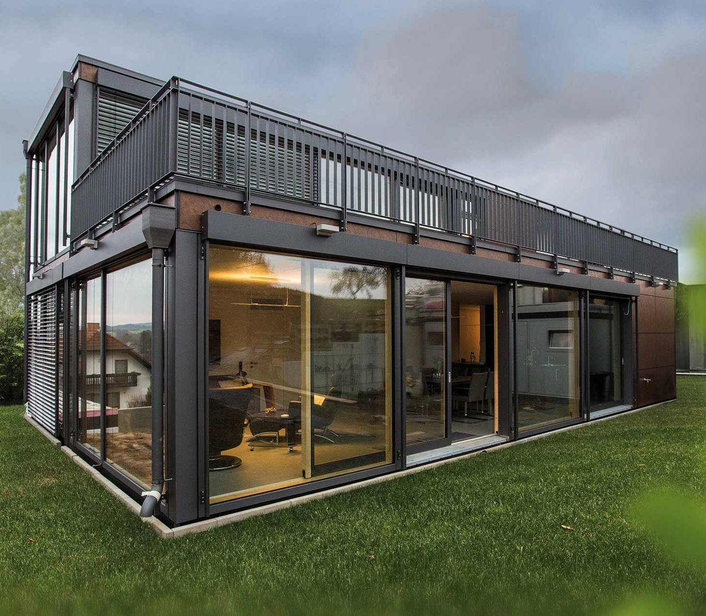 Two-storey prefab modular home with floor-to-ceiling glazing and roof terrace