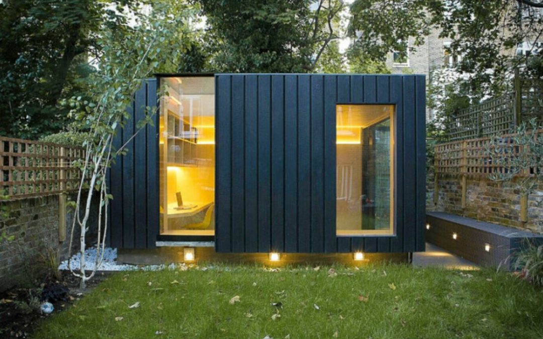 Compact dark-clad modular garden office at dusk